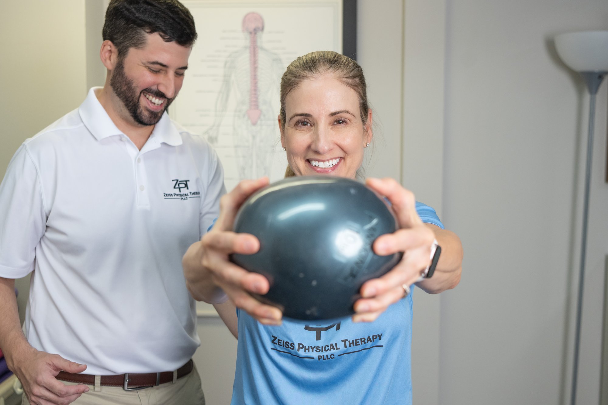 Patient holding a weighted exercise ball during a one-on-one session with Russell Zeiss, DPT